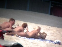 Thrilling nude friends are relaxing on a nudist beach