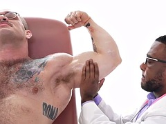 Muscular and oiled hunk masturbated by a black doctor in the infirmary